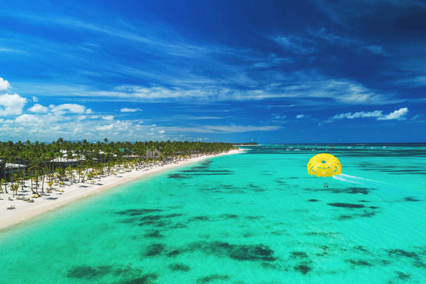 Тропический отпуск в Пунта-Кане, Доминиканская Республика. Вид с воздуха на пляжный курорт. Парасейлинг. Загорать
. - Фото, изображение