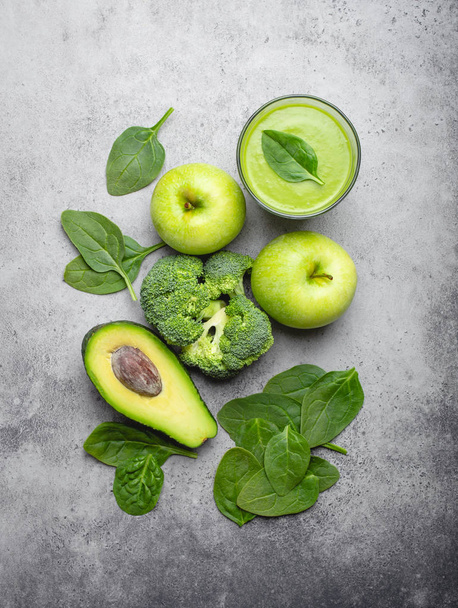 Ingredients for making green healthy smoothie, broccoli, apples, avocado, spinach over gray stone background. Clean eating, detox plan, vitamins, diet and weight loss concept. Close up, top view  - Photo, Image