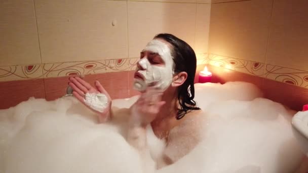 Mujer tomando baño en la bañera en el cuarto de baño 4k. Ella aplicación facial máscara de arcilla
. - Metraje, vídeo