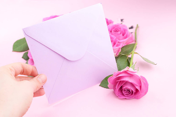 A bouquet of pink roses with petals on a pink background and a letter for text. Surprise in the concept of lovers day and mother's day. Flat lay. Copy space - Fotografie, Obrázek
