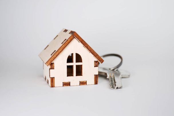 Dřevěný dům s klíčem na šedém pozadí, koncept pro prodej domů, s copyspace - Fotografie, Obrázek