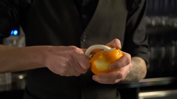 Бармен режет апельсиновую корку для свежего алкогольного напитка - Кадры, видео