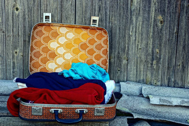 Open suitcase and clothes near the gray wall - Photo, Image