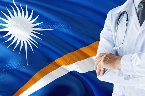 Doctor standing with stethoscope on Marshall Islands flag background. National healthcare system concept, medical theme. - Fotó, kép
