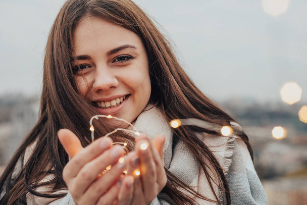 Muotokuva kaunis hymyilevä tyttö pitää lämpimiä tulipaloja käsissään
 - Valokuva, kuva