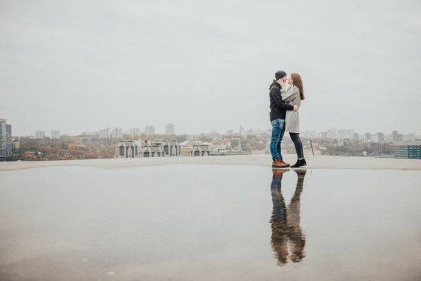 Loving couple on the roof of high-rise buildings on the background of panoramas of the city. Love in the reflection of water - Foto, imagen