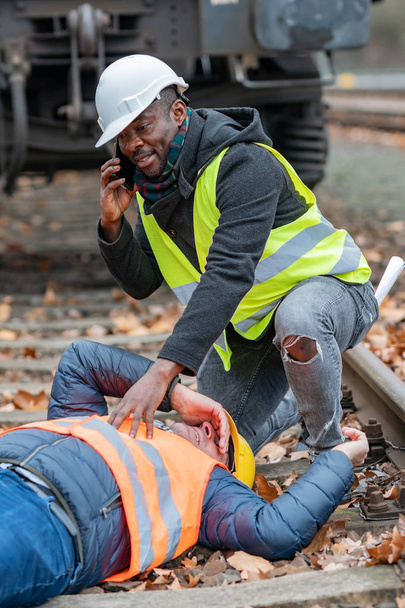 Railroad engineer injured in an accident at work on the railway tracks. Calling for help - Photo, Image
