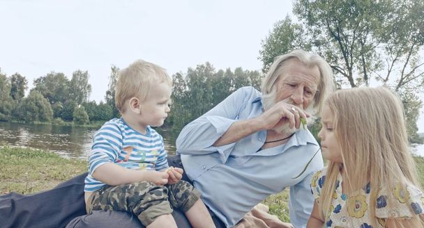 abuelo mayor caucásico con nieto y nieta pasar tiempo en la naturaleza
 - Foto, Imagen