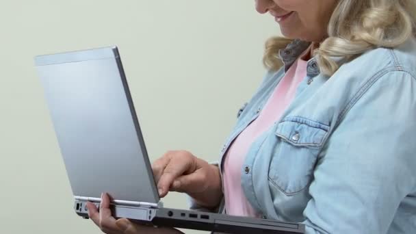 Female pensioner typing on laptop and smiling camera, online banking, internet - Filmagem, Vídeo