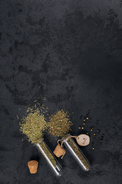 Assorted spices and herbs on dark black background. Seasonings for food. Rosemary and basil in glass flasks. Homemade spices ingredients for cooking - Fotoğraf, Görsel