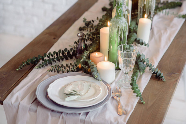 Wedding. Banquet. The chairs and table for guests, decorated with candles, served with cutlery and crockery and covered with a tablecloth. The table stands on a green lawn - 写真・画像