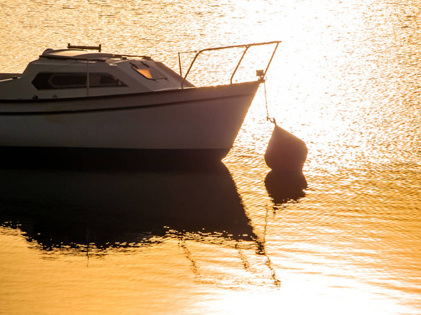 Boot op een meer bij zonsondergang, afgemeerd in het stuwmeer van La Maya, Spanje - Foto, afbeelding