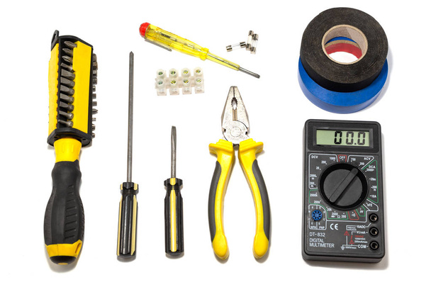 Een set van instrumenten voor de elektricien op een witte achtergrond: schroevendraaiers, tangen, isolatietape, voltmeter, zekeringen. - Foto, afbeelding