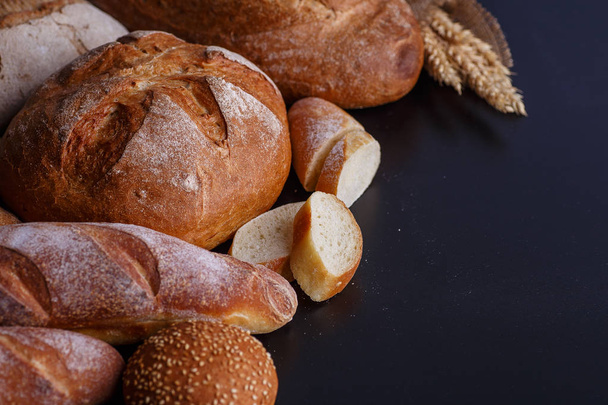 Хлібобулочні вироби - золотий сільський хліб з хліба та булочок на чорному крейдяному фоні
.  - Фото, зображення