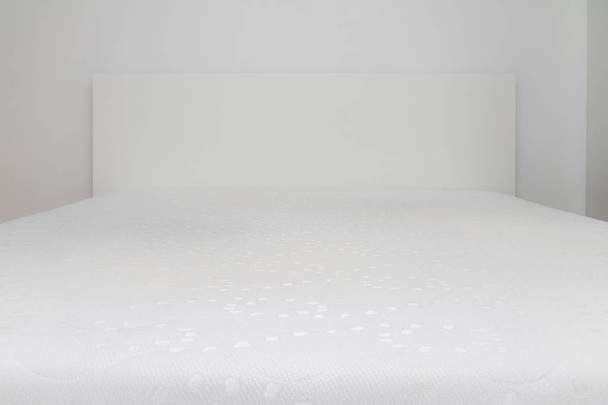Close up of memory foam mattress on the bed frame at sleeping room. Comfort, choosing mattress - Photo, Image