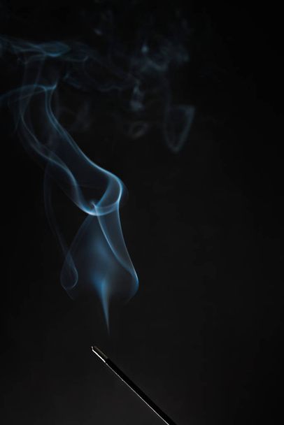 Κάπνισμα θυμιάματος ραβδί με καπνό ανεβαίνοντας πάνω σε μαύρο φόντο. Θέμα απόλυτης χαλάρωσης, καπνό ατμό, κύματα καπνού, ομίχλη και την ομίχλη επίδραση - Φωτογραφία, εικόνα