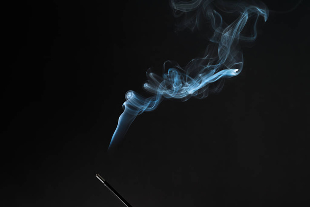 Smoking incense stick with smoke going up on Black Background. Pure relaxation theme, smoke steam, smoke waves, fog and mist effect - Foto, imagen