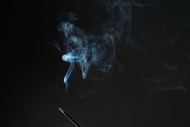 Smoking incense stick with smoke going up on Black Background. Pure relaxation theme, smoke steam, smoke waves, fog and mist effect - Foto, Imagem