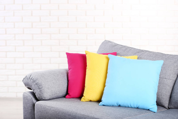 Modern grey sofa with colorful pillows on brick wall background - Foto, Imagem