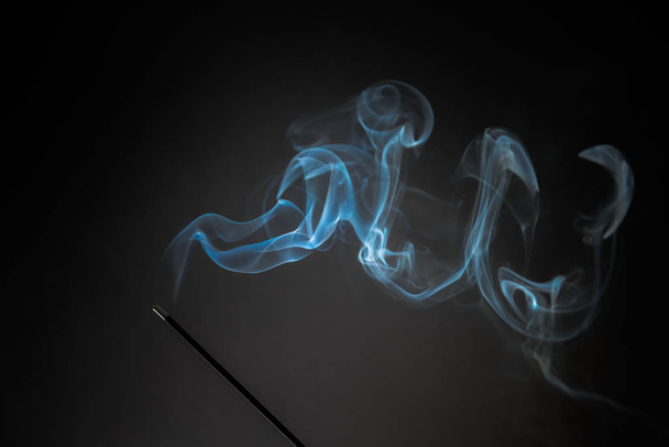 Палочка для курения с дымом на черном фоне. Тема чистого расслабления, дымовой пар, дымовые волны, эффект тумана и тумана
 - Фото, изображение