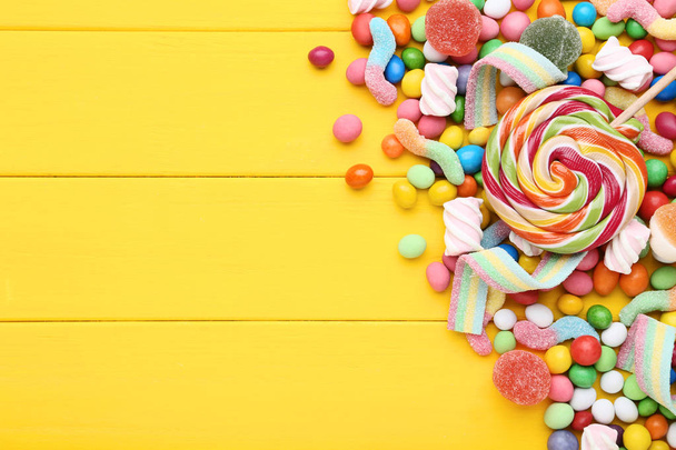 Sweet candies and lollipops on yellow wooden table - Foto, imagen
