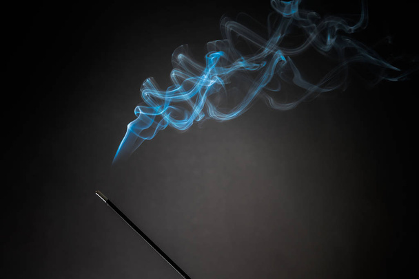 Räucherstäbchen mit aufsteigendem Rauch auf schwarzem Hintergrund. Entspannungsthema pur, Rauchdampf, Rauchwellen, Nebel- und Nebeleffekt - Foto, Bild