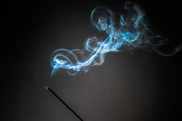 Räucherstäbchen mit aufsteigendem Rauch auf schwarzem Hintergrund. Entspannungsthema pur, Rauchdampf, Rauchwellen, Nebel- und Nebeleffekt - Foto, Bild