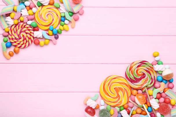 Dulces caramelos y piruletas sobre mesa de madera rosa
 - Foto, imagen