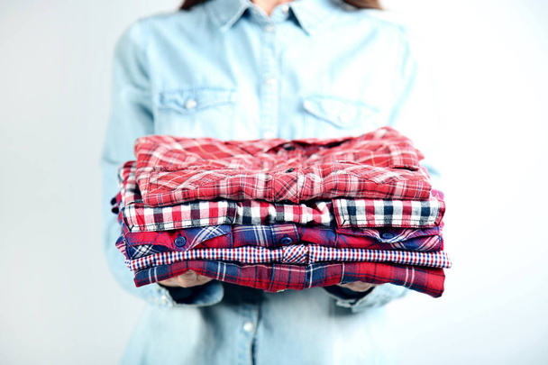 Female hands holding folded shirts - 写真・画像