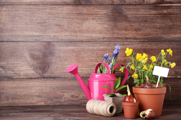 Watering can with flowers in pots on wooden table - Foto, Imagem