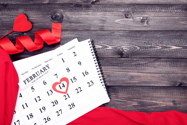 Valentine day calendar with red hearts and ribbon on wooden table - 写真・画像