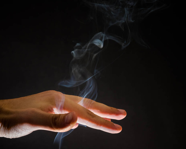 Rauch steigt durch menschliche Hand auf. Geister, spiritueller Hintergrund, Hexerei - Foto, Bild