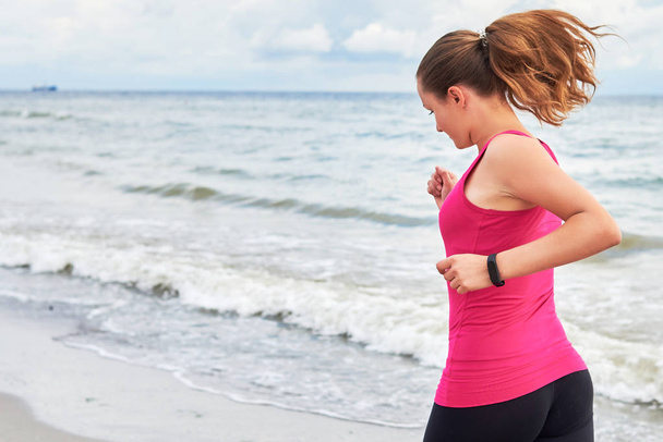 Mujer atlética corriendo en la playa del mar, espacio para copiar. Corredora haciendo ejercicio en la mañana de verano. concepto de estilo de vida saludable
 - Foto, Imagen