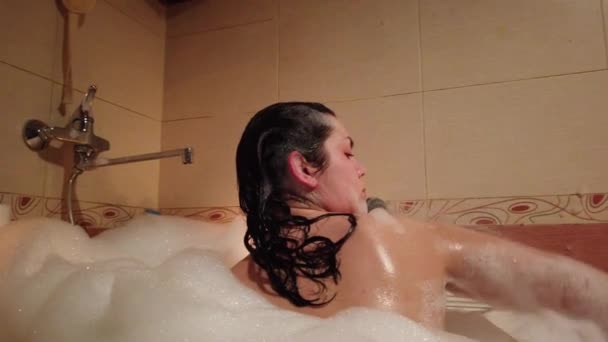 Atractiva joven mujer tomando un baño de burbujas por la quema de velas
 - Metraje, vídeo
