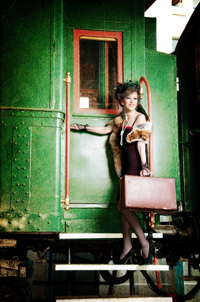 Retro girl with suitcase near the old train - 写真・画像