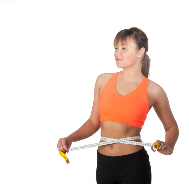 Beautiful slim woman measuring her waistline with a measuring tape - Photo, Image