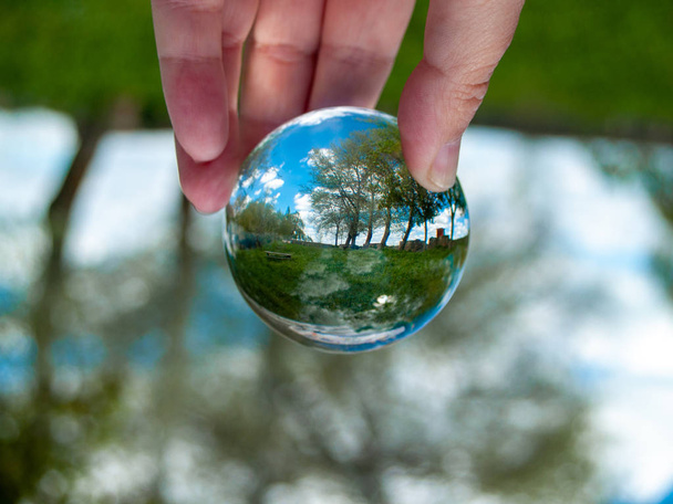  persona con una bola de cristal en la mano con un reflejo del paisaje
 - Foto, Imagen
