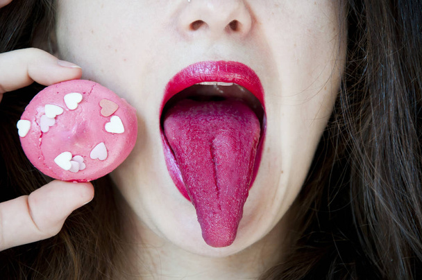 Glamour macro shoot with sexy woman's lips with a sweet bonbon. Beautiful bright fashion make-up. Girl licking a raspberry meringue. Healthy teeth, funny smile. valentines day concept and dieting. - Photo, image