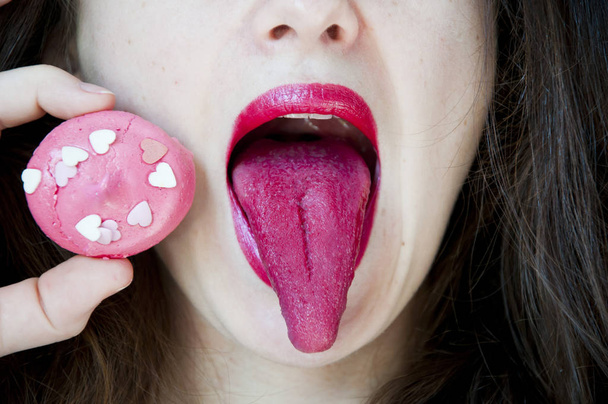 valentines day concept and dieting. Glamour macro shoot with sexy woman's lips with a sweet bonbon. Beautiful bright fashion make-up. Girl licking a raspberry meringue. Healthy teeth, funny smile. - Photo, Image