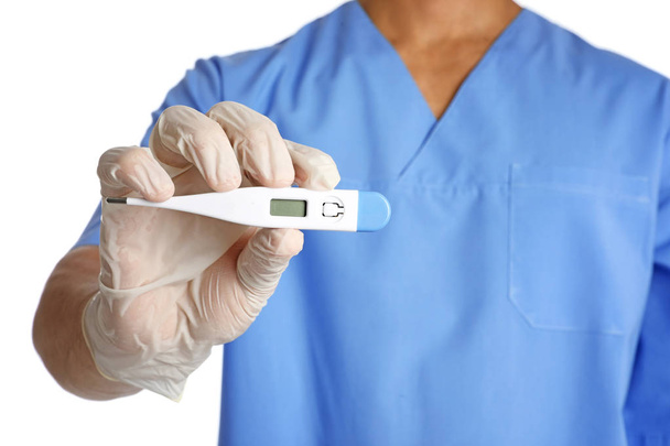 Male doctor holding digital thermometer on white background, closeup. Medical object - Foto, Bild