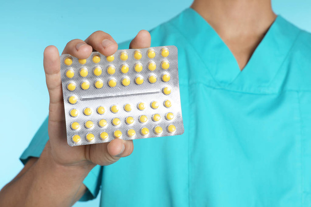 Male doctor holding pills on color background, closeup. Medical object - Φωτογραφία, εικόνα