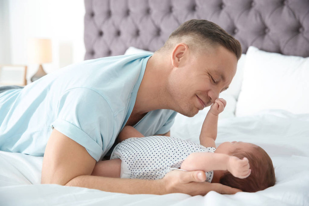 Man with his newborn baby on bed - Foto, afbeelding
