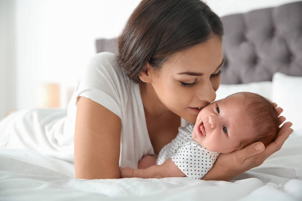 Young woman with her newborn baby on bed - Foto, Bild