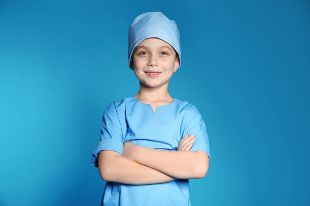 Cute little child in doctor uniform on color background - Photo, Image