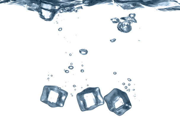 Ice cubes falling into water against white background - Foto, afbeelding