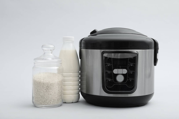 Modern electric multi cooker, rice and milk on grey background - Zdjęcie, obraz