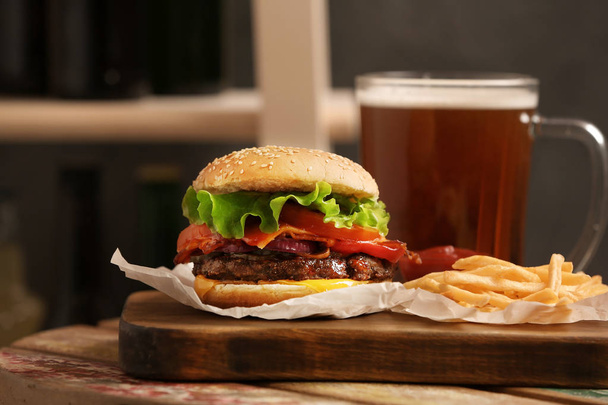 Burger, beer and french fries on table indoors - Foto, immagini