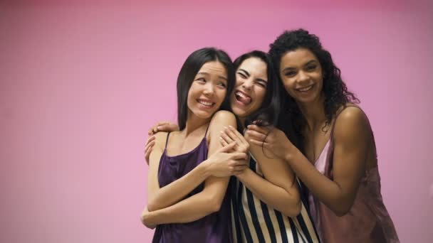 Mujeres multiraciales en pijama abrazándose y posando en cámara, divirtiéndose juntas
 - Metraje, vídeo
