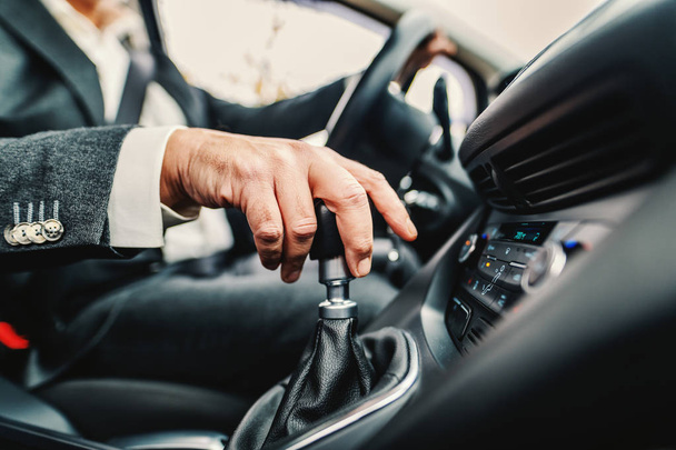 Close up of Caucasian man holding hand on gearshift and changing speed. - Foto, afbeelding