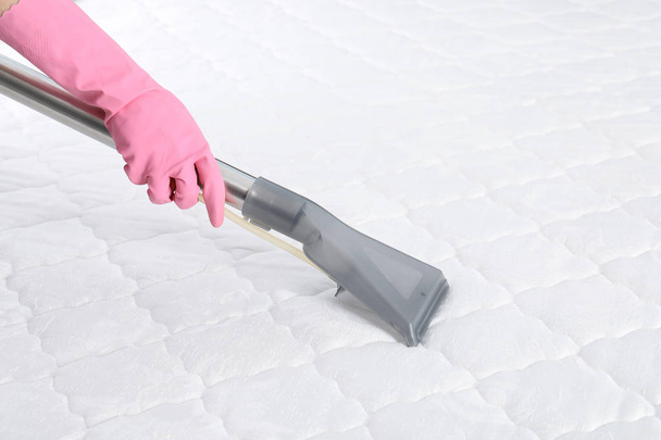 Persona desinfectando colchón con aspiradora, primer plano. Espacio para texto
 - Foto, imagen